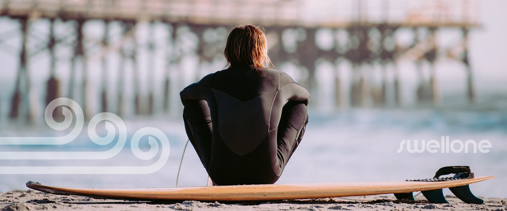 Surfer sitting on surfboard, watching the waves roll in.